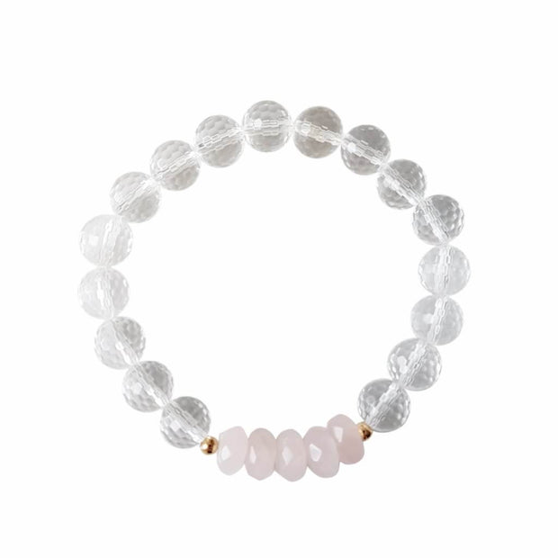Close up image on a white background of a stretchy Rose Quartz and Clear Quartz mala bracelet. The bracelet has four faceted roundel beads made of Rose Quartz. The rest of the bracelet is made with 8mm faceted round Clear Quartz beads. Two small 2mm gold filled beads flank the Rose Quartz beads to separate them from the Clear Quartz.