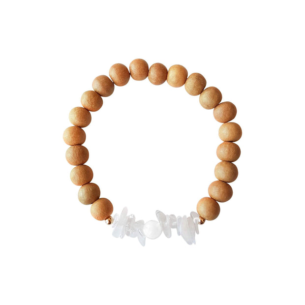 Close up image on a white background of a sandalwood mala bracelet. The bracelet has a 6mm round faceted mother of pearl bead flanked by half an inch of chipped moonstone on each side. The remainder of the bracelet is 8mm sandalwood beads.